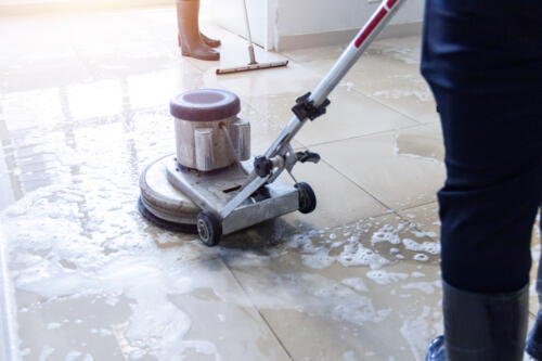 Janitor use floor scrubber machine on the floor hallway office building or walkway after school and classroom work job with sun light background. Ein Fensterreiniger säubert ein Fenster mit einem Abzieher.