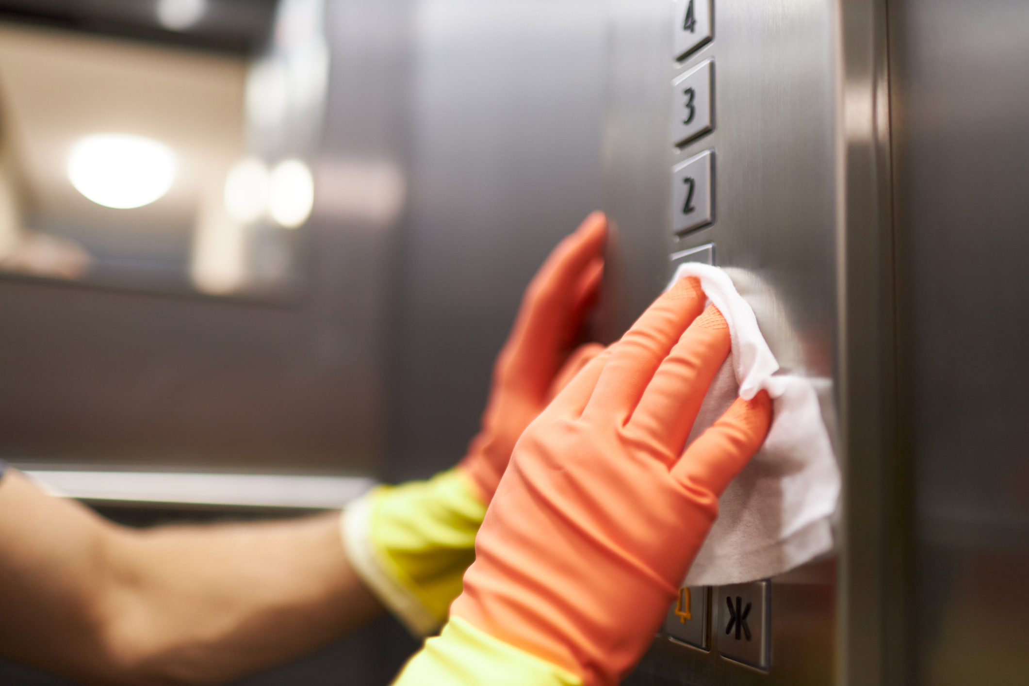 Different photos of a woman and a man disinfecting and cleaning an elevator with disinfectant wipes while wearing rubber gloves Ein Fensterreiniger säubert ein Fenster mit einem Abzieher.